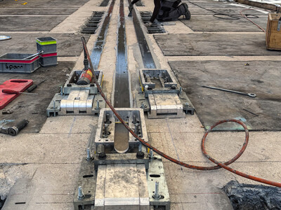 A hydraulic jack applies tension to the CFRP laminates.